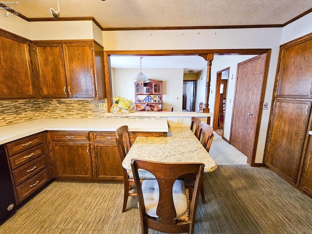 kitchen featuring ornate columns, a kitchen bar, kitchen peninsula, decorative backsplash, and hanging light fixtures