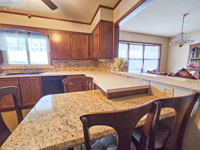 kitchen with a kitchen bar, backsplash, hanging light fixtures, crown molding, and sink