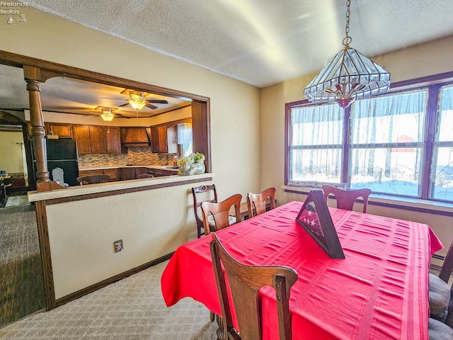 dining room featuring ceiling fan, light carpet, a wealth of natural light, and a textured ceiling