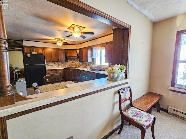 kitchen featuring sink, backsplash, black fridge, kitchen peninsula, and custom range hood