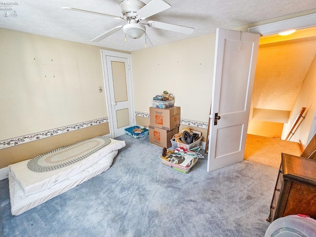 bedroom with ceiling fan, light colored carpet, and a textured ceiling