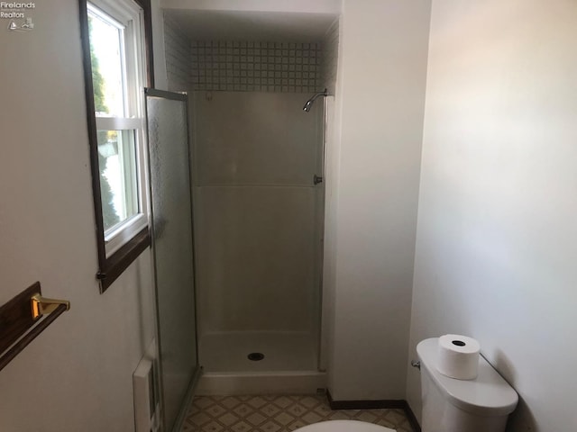 bathroom featuring toilet and a shower with door