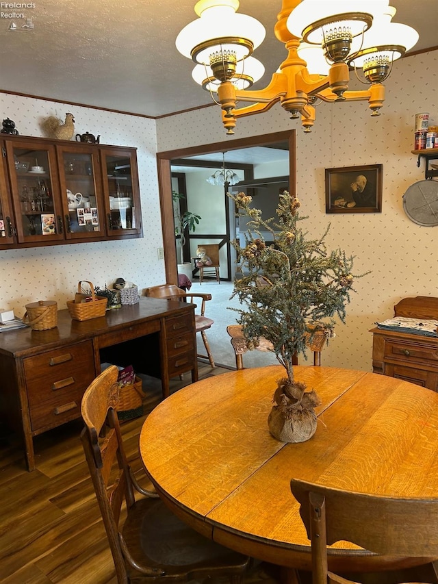 dining room featuring dark hardwood / wood-style flooring, an inviting chandelier, ornamental molding, and a textured ceiling