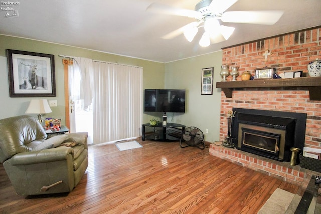 living room with ceiling fan, a brick fireplace, and hardwood / wood-style flooring