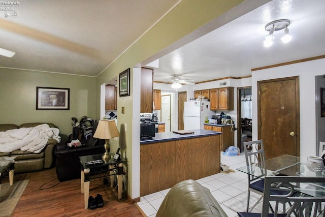 kitchen featuring kitchen peninsula, ceiling fan, light tile patterned flooring, ornamental molding, and white refrigerator