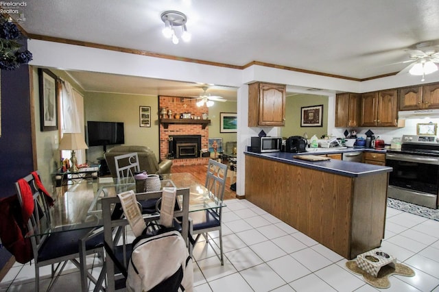 kitchen with appliances with stainless steel finishes, ornamental molding, kitchen peninsula, and light tile patterned flooring