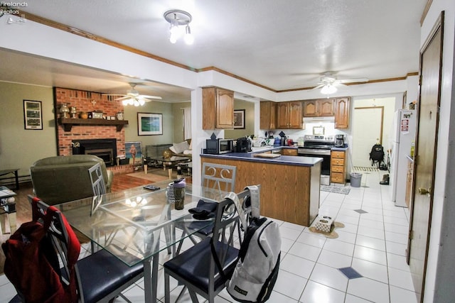 kitchen with a fireplace, kitchen peninsula, light tile patterned flooring, appliances with stainless steel finishes, and ornamental molding