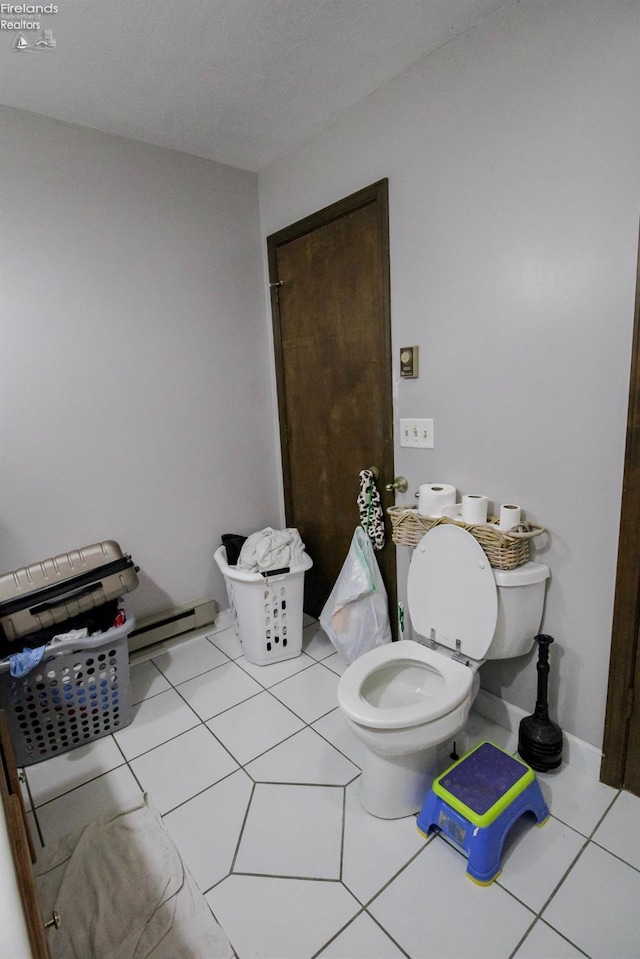 bathroom with baseboard heating, toilet, and tile patterned flooring