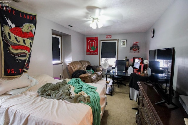 bedroom with ceiling fan, carpet, and a textured ceiling