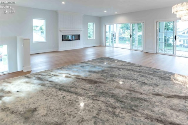 unfurnished living room with hardwood / wood-style floors, a chandelier, and a large fireplace