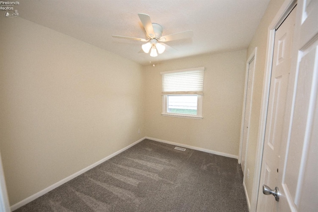 unfurnished bedroom with ceiling fan and dark colored carpet