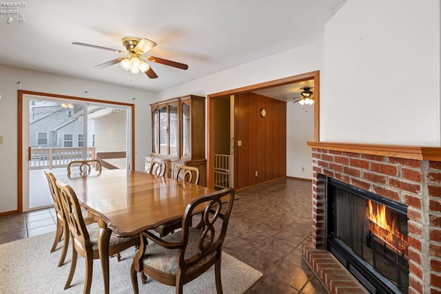 tiled dining area featuring ceiling fan and a fireplace