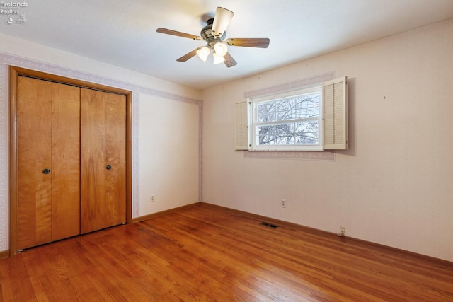 unfurnished bedroom with ceiling fan, a closet, and hardwood / wood-style flooring