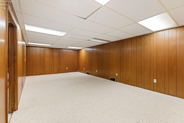 basement featuring a paneled ceiling and carpet flooring