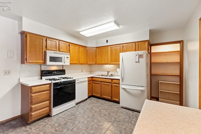 kitchen with backsplash, sink, white appliances, and a textured ceiling