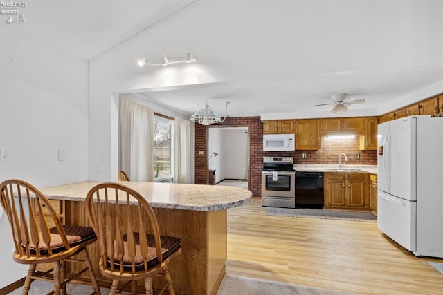 kitchen featuring white appliances, decorative backsplash, sink, a kitchen breakfast bar, and light hardwood / wood-style flooring