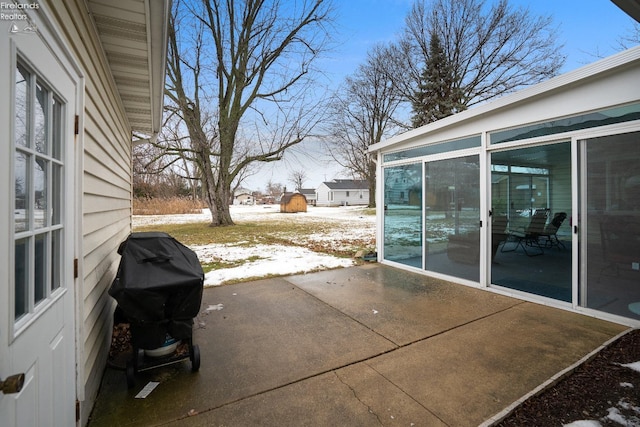 snow covered patio featuring a sunroom and area for grilling