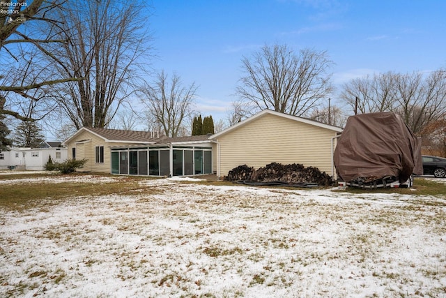 snow covered back of property with a sunroom