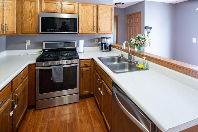 kitchen featuring stainless steel appliances, kitchen peninsula, sink, and hardwood / wood-style floors