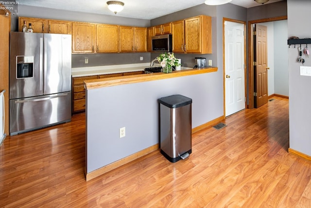 kitchen featuring light hardwood / wood-style flooring, stainless steel appliances, and kitchen peninsula