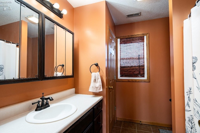 bathroom featuring tile patterned flooring, vanity, and a textured ceiling