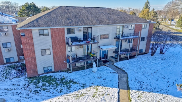 snow covered back of property featuring a balcony