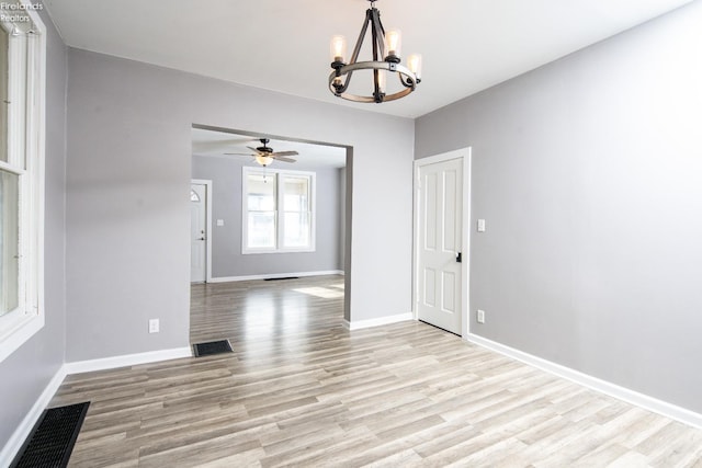 unfurnished dining area featuring ceiling fan with notable chandelier and light hardwood / wood-style flooring