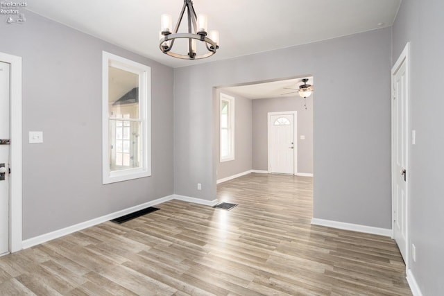 interior space with a healthy amount of sunlight, ceiling fan with notable chandelier, and light hardwood / wood-style flooring