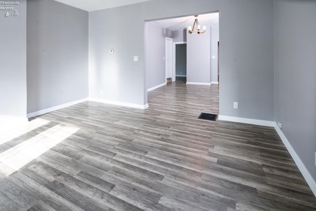 empty room featuring wood-type flooring and a chandelier