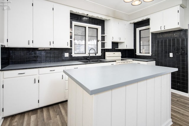 kitchen with a kitchen island, sink, white cabinets, dark wood-type flooring, and electric stove