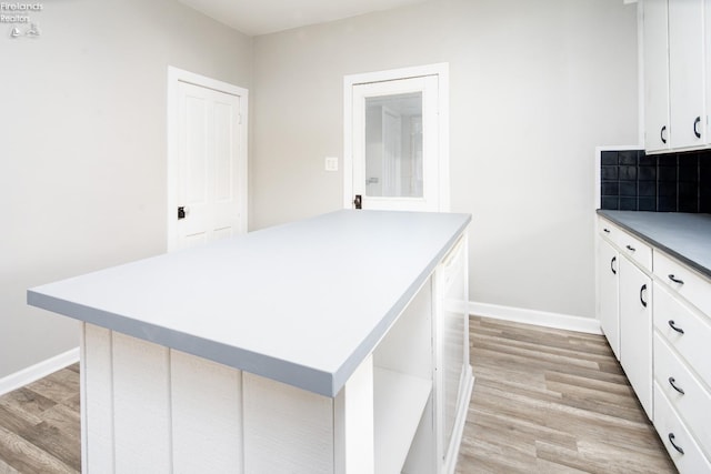 kitchen featuring a kitchen island, white cabinets, backsplash, and light hardwood / wood-style flooring