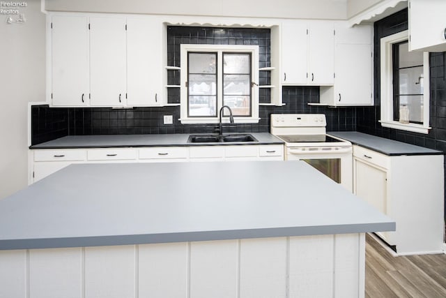 kitchen with electric stove, sink, white cabinetry, and light wood-type flooring