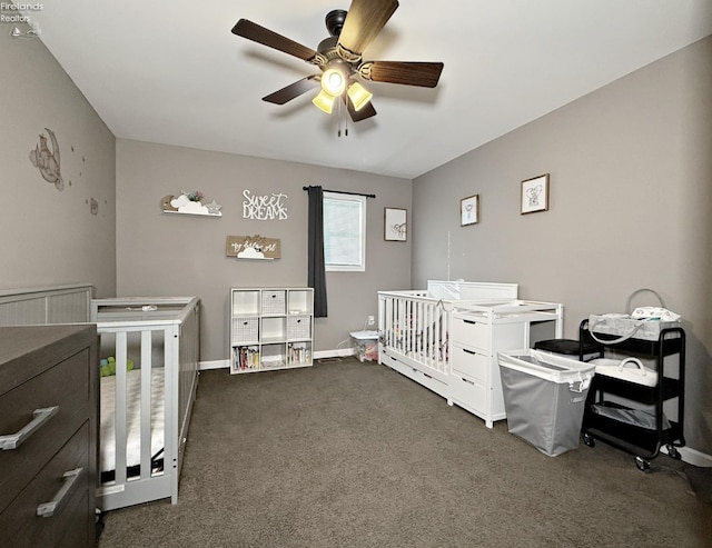 bedroom featuring dark carpet, a nursery area, and ceiling fan