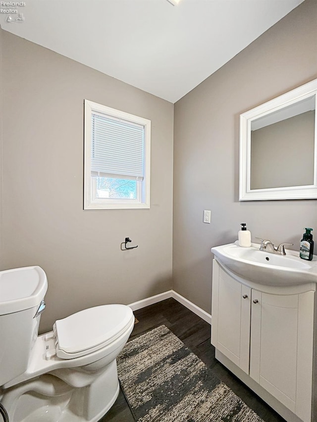 bathroom with toilet, hardwood / wood-style floors, and vanity