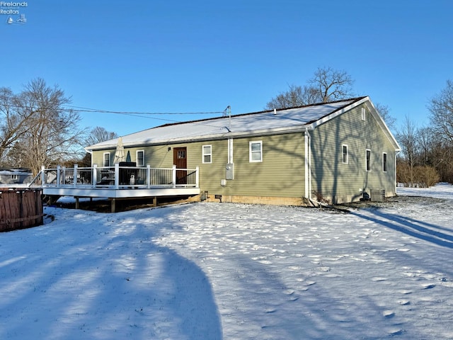 snow covered rear of property with a deck