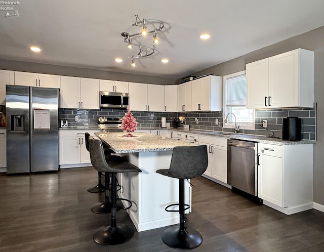 kitchen featuring white cabinetry, appliances with stainless steel finishes, dark hardwood / wood-style floors, and a kitchen island