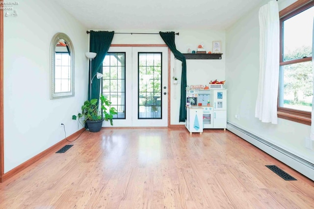 interior space with baseboard heating, a wealth of natural light, and light wood-type flooring