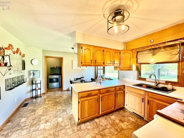 kitchen featuring kitchen peninsula, sink, decorative light fixtures, a textured ceiling, and range