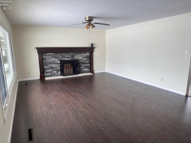 unfurnished living room featuring dark wood-type flooring, ceiling fan, a fireplace, and a wealth of natural light