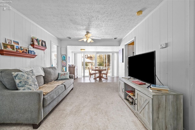 carpeted living room featuring wood walls, a textured ceiling, and ceiling fan