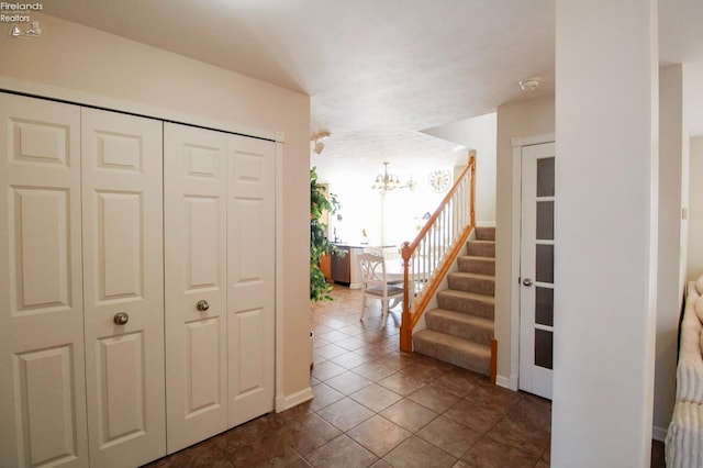 corridor with a notable chandelier and dark tile patterned floors