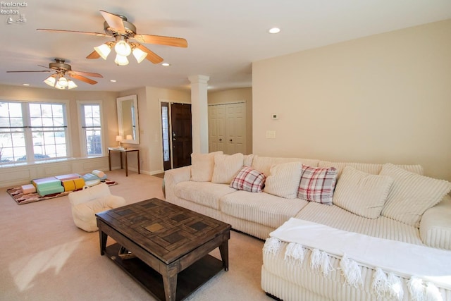 living room featuring ceiling fan, light carpet, and ornate columns