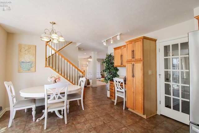 dining area with decorative columns, ceiling fan with notable chandelier, and a textured ceiling