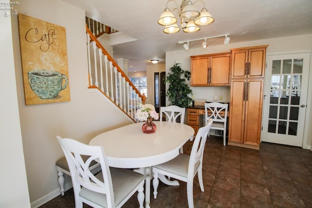 dining area with dark tile patterned floors and a notable chandelier