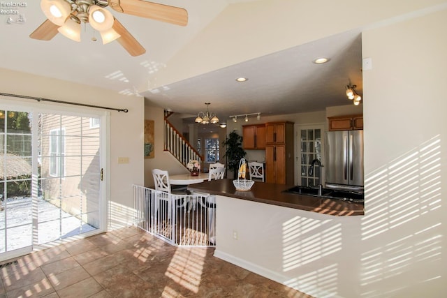 kitchen with kitchen peninsula, vaulted ceiling, stainless steel fridge, sink, and a breakfast bar area