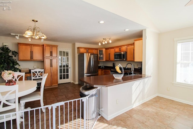 kitchen with pendant lighting, appliances with stainless steel finishes, lofted ceiling, sink, and kitchen peninsula