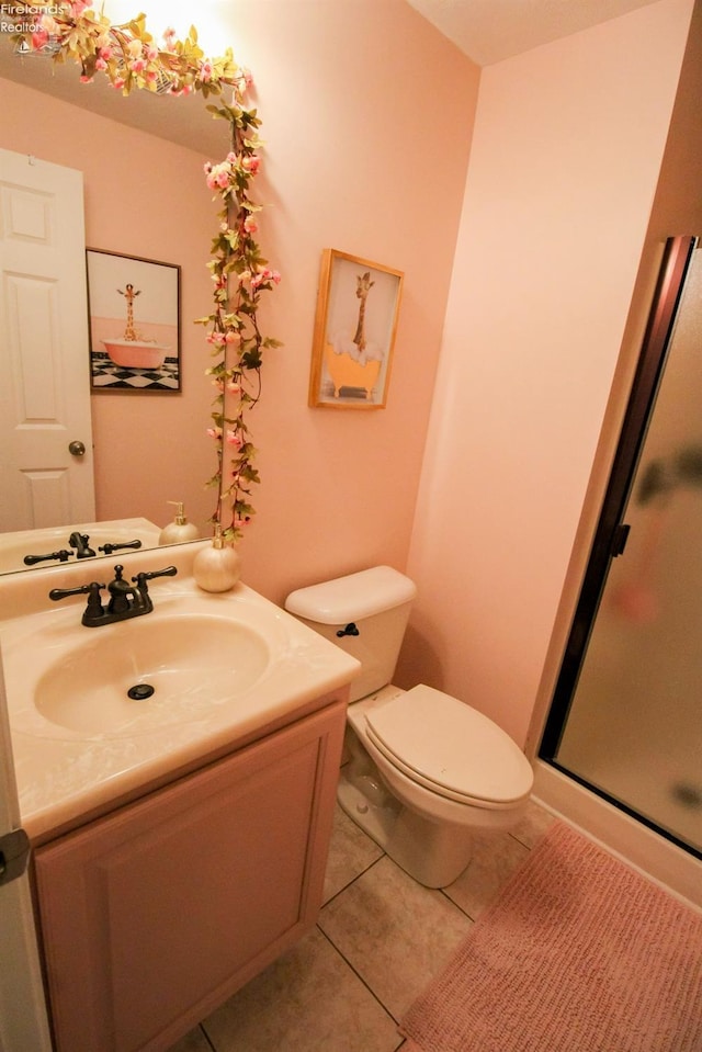 bathroom featuring toilet, a shower with shower door, tile patterned floors, and vanity