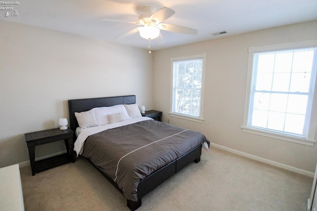 bedroom with ceiling fan, multiple windows, and light carpet