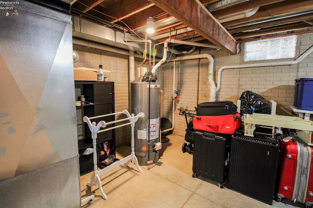 basement featuring brick wall and gas water heater