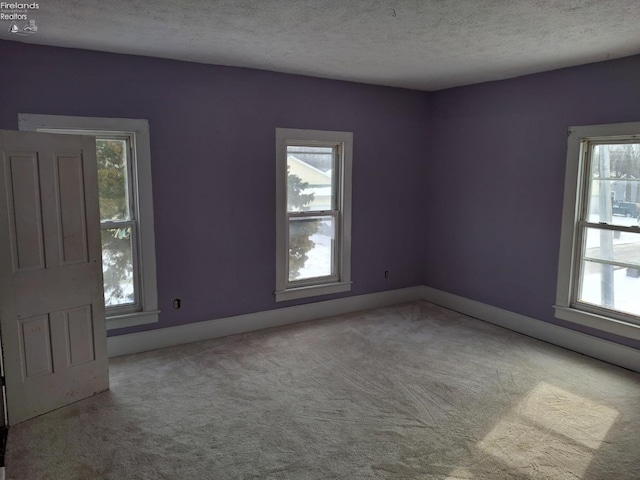 carpeted empty room featuring a textured ceiling